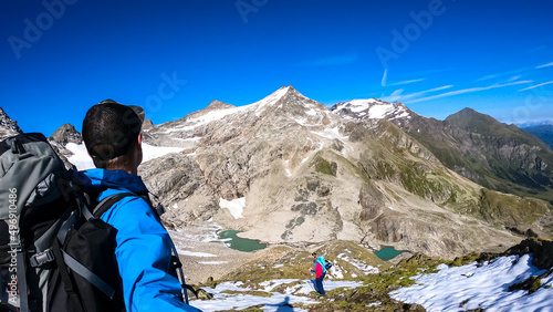 Couple with scenic view on Hoher Sonnblick in High Tauern mountains in Carinthia, Salzburg, Austria, Europe, Alps. Woman leading the way, man is taking selfies. Landscape in Hohe Tauern National Park photo