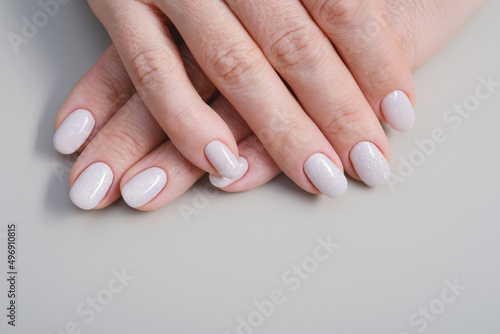 Perfect artificial fingernails of adult woman. Female hands with pearl beige nails. Care for sensuality female hands. Shallow depth of field
