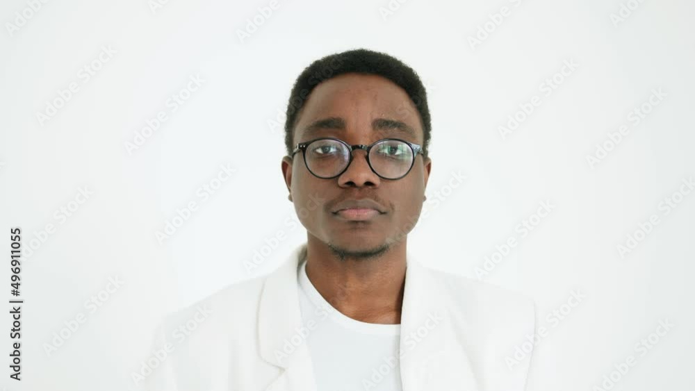 Portrait of a serious young african american man in glasses in a white suit against a white studio background. Slow motion Portrait of a serious young african american man in glasses in a white suit against a white studio background. Slow motion