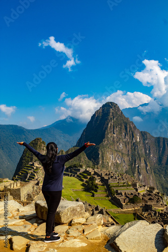 Toma vertical de una mujer caucásica mirando la antigua ciudad de Machu Picchu conbrazos abiertos,estilo de vida,concepto de turismo,