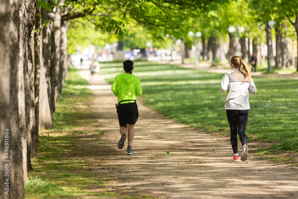 Un homme et une femme en train de faire une course ou un jogging sur un chemin dans un parc.