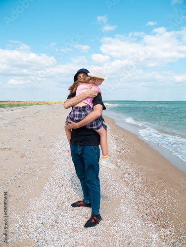 Happy family father daughter hugging on marine landscape. Bearded dad with child in hands having fun together looking on sea water. Authentic lifestyle real people. Travel Fathers day Southern Ukraine © KawaiiS