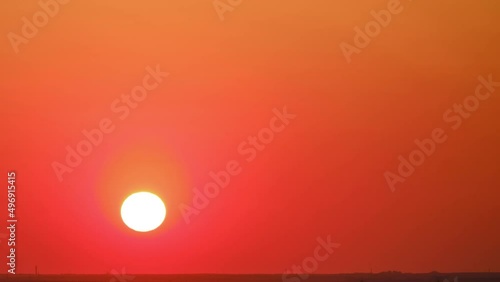 Sunrise in a clear cloudless sky, time lapse. The big yellow sun rises below the horizon in the morning sky at twilight, timelapse