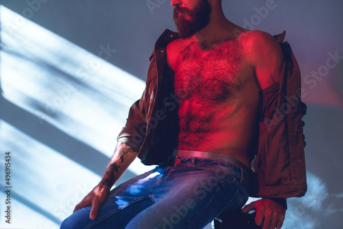 Portrait of a brutal bearded man with a naked torso.
