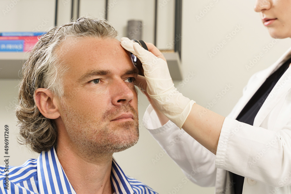 Dermatologist is using dermatoscope for facial skin examination. Dermatologist is using dermatoscope for facial skin examination.