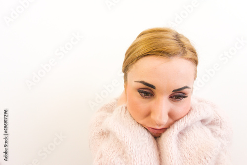 Close-up portrait of sad thoughtful woman with blonde hair wearing soft pink sweater. Depression, personal problems, loneliness concepts