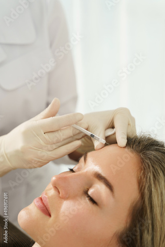 Woman during facial filler injections in aesthetic medical clinic