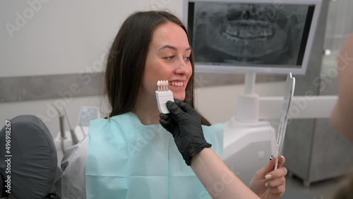 Dentist at work in dental clinic. Matching the shades of the implants using shade guide. Preparation for teeth whitening or implantation in dental office.