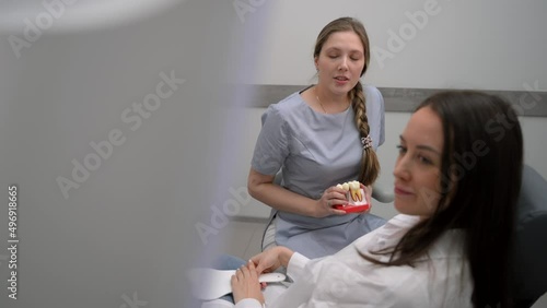 Dentist with a patient looking at a tomographic image of the teeth and discussing a treatment and implantation plan