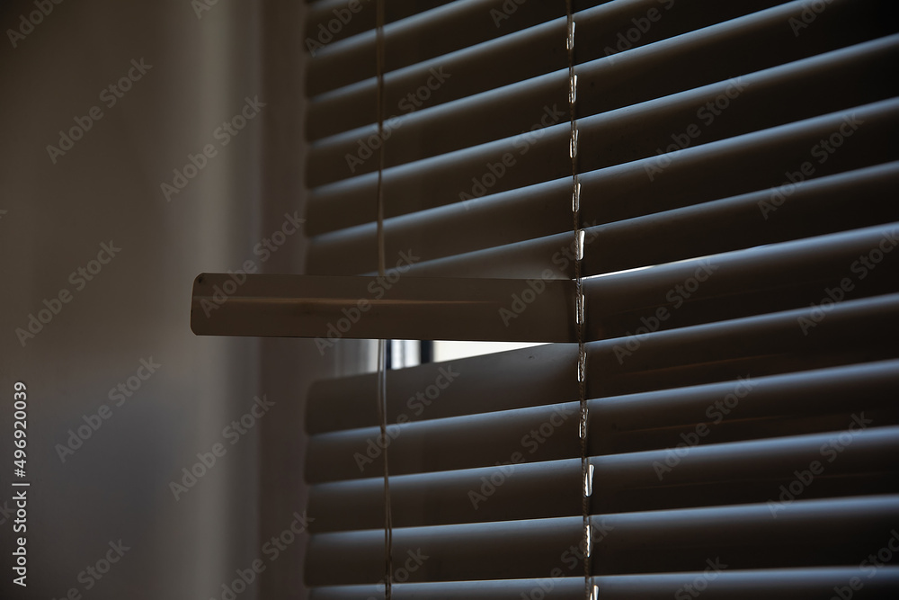 Broken closed blinds on the window in the room. Broken closed blinds on the window in the room.
