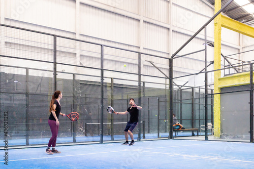 Young Caucasian couple playing paddle tennis on indoor courts