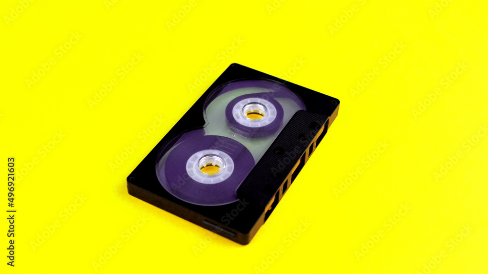 One black audio cassette on a yellow background One black audio cassette on a yellow background
