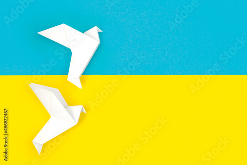 Two white origami paper doves on colors of flag of Ukraine. The concept of peace between two states. Symbol of peace on blue and yellow background. Independence. Stop war. Copy Space for text