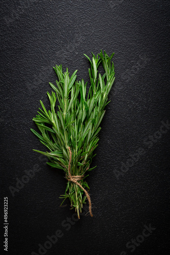 Bunch of green organic rosemary spice on black surface