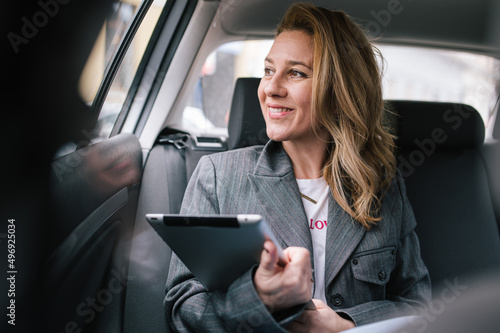 A business woman uses a tablet in the back seat of a car. photo