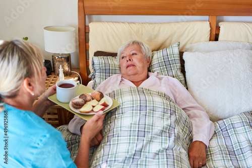 Pflegekraft vom Pflegedienst serviert Frühstück für Seniorin photo