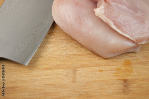 Kitchen knife and pieces of meat on wood cutting board. Top view