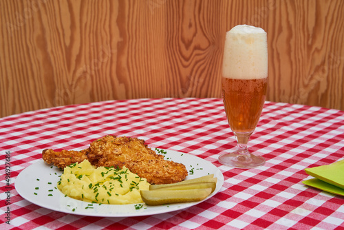 Billede på lærred Chicken escalope or schnitzel served on white porcelain plate with sweet and sour pickled cucumbers and mashed potatoes as a side dish and glass of czech pilsner beer