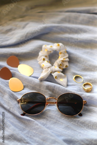 Blue linen shirt, sunglasses, white scrunchie, gold rings and fashionable earrings. Selective focus.