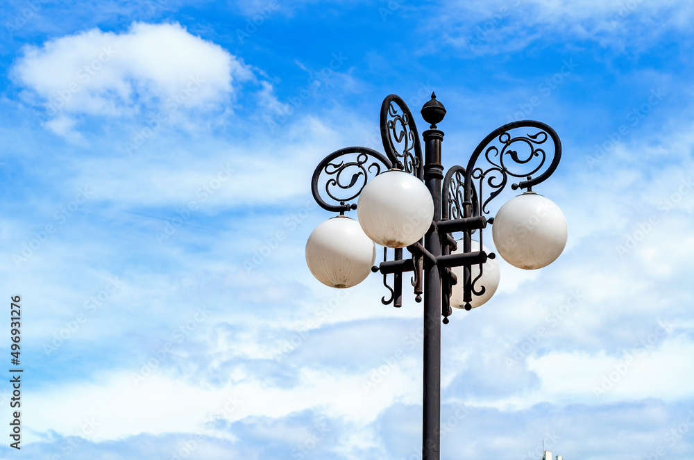 Street lamp on a background of sky. White spherical lamps, iron patterns. Street lighting in the city. Street lamp on a background of sky. White spherical lamps, iron patterns. Street lighting in the city.