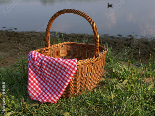 Picnic basket and red gingham cloth by the lake 
