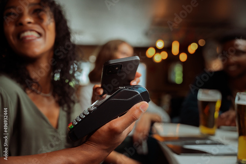 african american female tapping card machine with cellular device