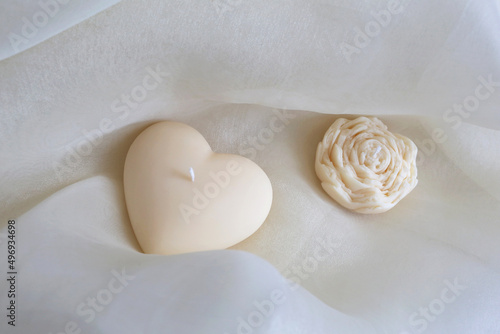 Handmade candle heart and flower on the gentle textile background. Natural eco-friendly home decor. Spa composition.