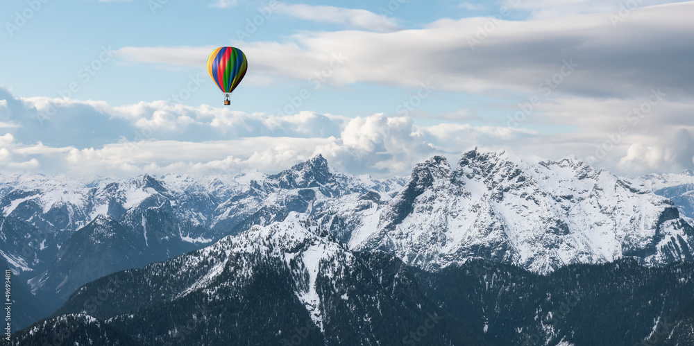 Dramatic Mountain Landscape covered in clouds and Hot Air Balloon Flying.