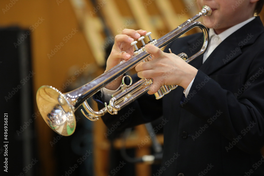 Obraz premium A person playing a silver trumpet in a black classical suit hands holding a musical instrument the musician's fingers on the keys a close-up shot from the concert