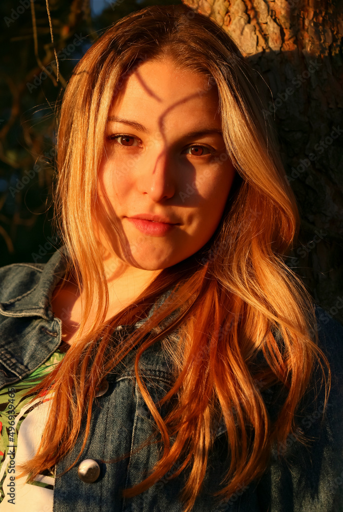 portrait of a tender young girl with brown eyes. Shadows in the sunset sunlight on the face in the park portrait of a tender young girl with brown eyes. Shadows in the sunset sunlight on the face in the park