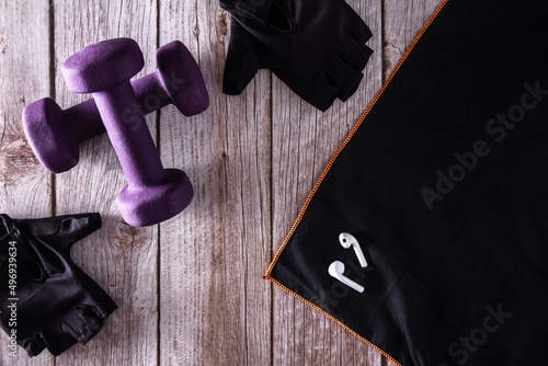 Purple fitness dumbbells with sports gloves and headphones. Gym accessories. Copy space. Selective focus.