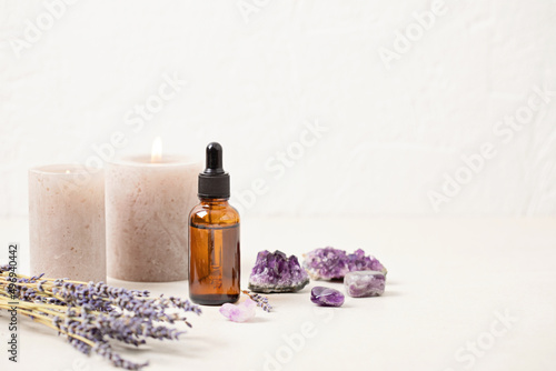 Glass bottle of Lavender essential oil with lavender flowers and candles and amethyst crystals. Meditation, zen, aromatherapy,spa massage concept