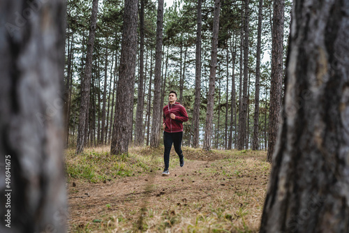 Side view full length of one man young caucasian male running trough the woods in nature outdoor jogging in autumn or spring day - sport fitness and recreation concept real people copy space