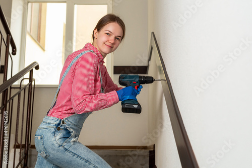 young female blue collar manual labour worker uses cordless screwdriver on constructions site