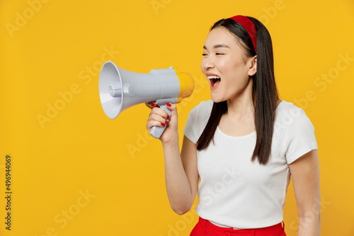 Vászonkép Promoter charming young girl woman of Asian ethnicity 20s years old wears white t-shirt hold scream in megaphone announces discounts sale Hurry up isolated on plain yellow background studio portrait