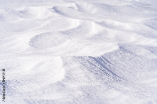 Freshly fallen snow surface looking like dunes shaped by wind. Winter abstract snow texture background.