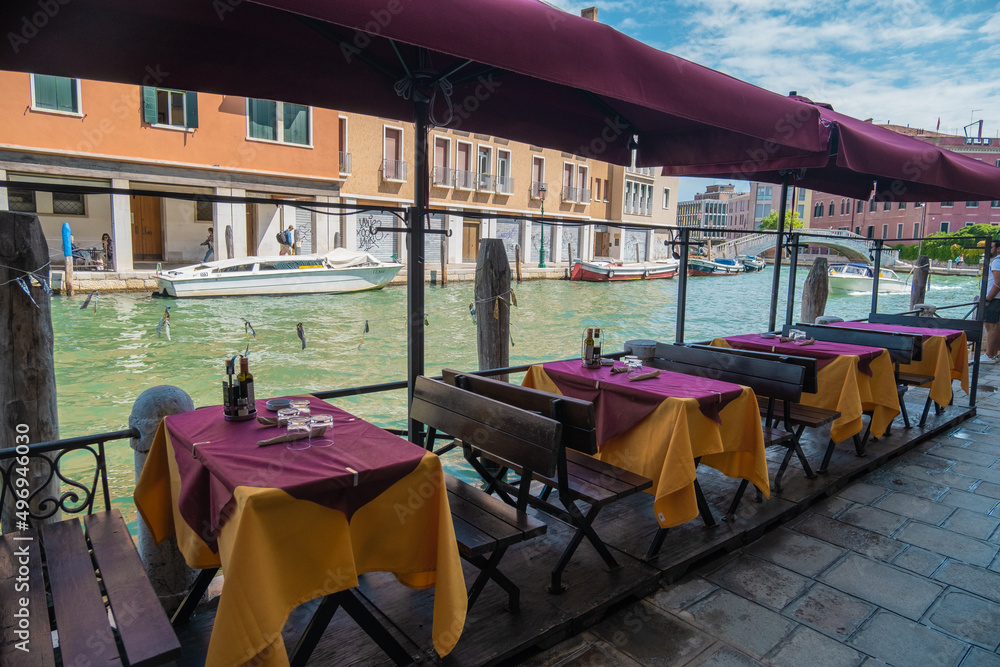 Naklejka premium VENICE, ITALY - August 27, 2021: View of empty restaurant tables due to the pandemic on the canals of Venice
