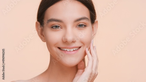 Close-up beauty portrait of young good-looking woman who softly touches her cheek and jaws with fingers | Perfect skin and beauty care concept.