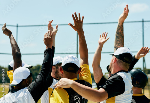 Raise your hand if youre about to give in your best. Cropped shot of a team of young baseball players cheering with their arms raised while standing on the field during the day. photo