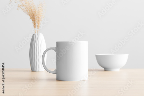 White mug mockup with a dry flower decoration on the wooden table.