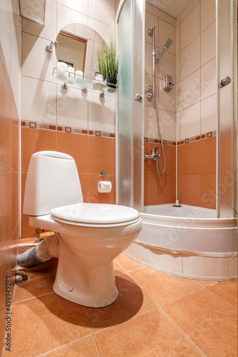 toilet and detail of a corner bidet cabin with wall mount shower attachment