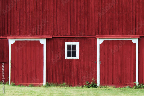 red farm barn hanging doors shadows trees overcast sunny green grass rural farming harvest building