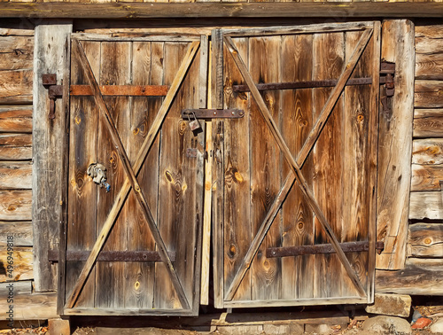 Double old wooden door with a lock on a dilapidated barn wall