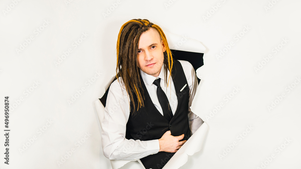 Young man with dreadlocks looking at camera and smiling. Handsome male in white shirt, black vest and tie with positive facial expression in hole of white background. Young man with dreadlocks looking at camera and smiling. Handsome male in white shirt, black vest and tie with positive facial expression in hole of white background.