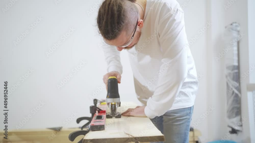 carpenter in protective glasses cuts wood with electric jigsaw carpenter in protective glasses cuts wood with electric jigsaw