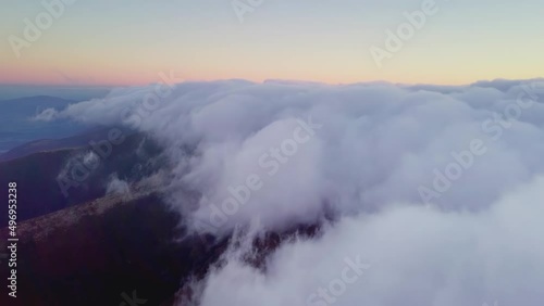 4K Drone flies in the clouds. Flight through the clouds during sunrise, top view of the clouds from the drone. National Park Shipit Karpat. Carpathians, Pylypets, Ukraine.  photo