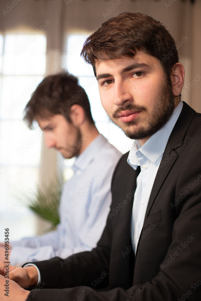 jeunes employés ou hommes d'affaires qui travaillent côte à côte au bureau avec des ordinateurs portables. Ils collaborent et travaillent en équipe. Sourire et réussite de la carrière. jeunes employés ou hommes d'affaires qui travaillent côte à côte au bureau avec des ordinateurs portables. Ils collaborent et travaillent en équipe. Sourire et réussite de la carrière.