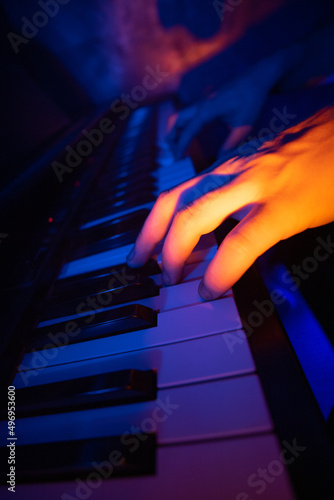 Canvas Print gros plan sur des mains qui jouent du piano dans une ambiance nocturne avec des lumières bleues et orange