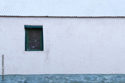 Plastered White Farmhouse Wall With Window And Sheet Roof