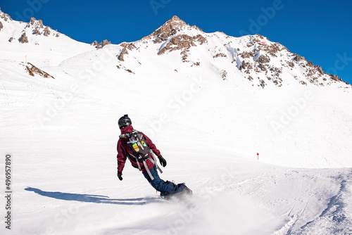Rear view of skier in sportswear with backpack skiing on snowy mountain